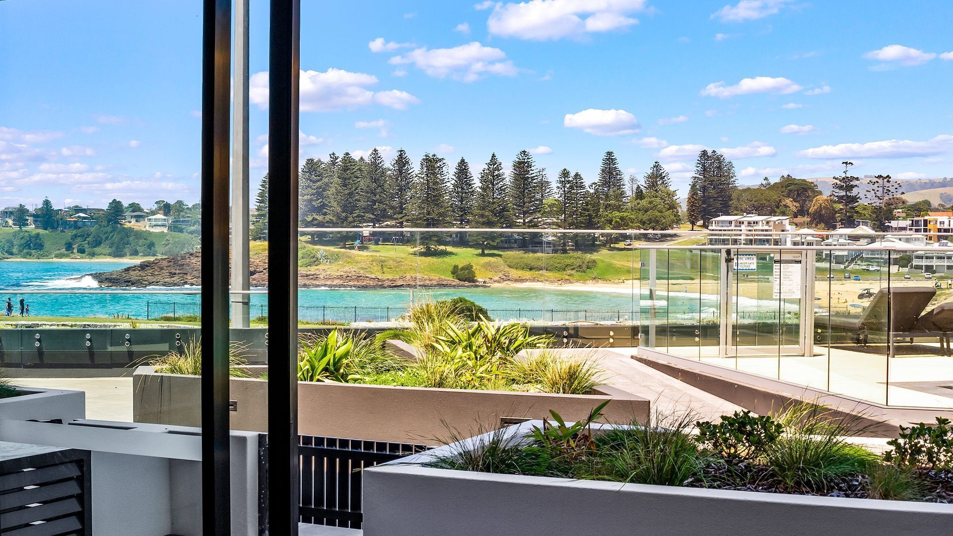A balcony with a view of a coastal area, including a beach and a forest.