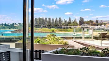 A balcony with a view of a coastal area, including a beach and a forest.