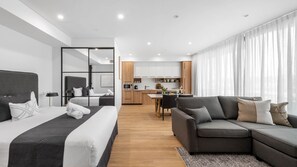Ein modernes Hotelzimmer mit Bett, einer Couch, einem Essbereich und einer Küche.