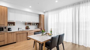 Eine moderne Küche mit weißen Schränken, einer Holzausziehtafel und einem Essbereich mit einem Marmortisch und Stühlen.