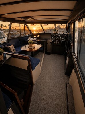 A boat interior with a sofa, table, and steering wheel.