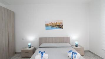 Habitación de hotel con cama, dos mesitas de noche, un armario de madera y un cuadro colgado en la pared.