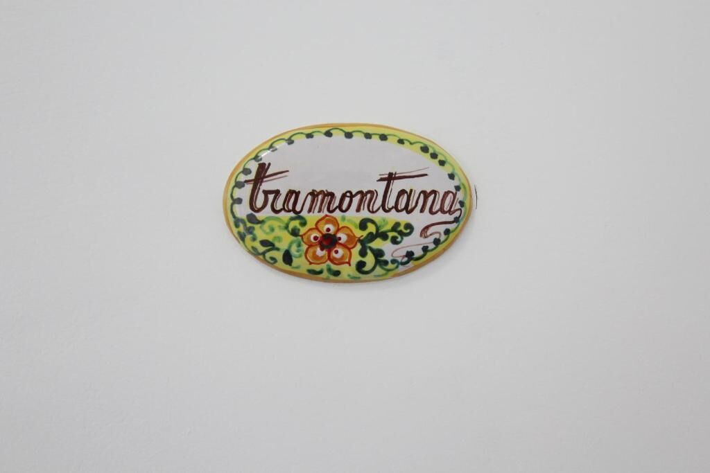 Ein oval geformtes Schild mit dem Text 'tramontana' und einem floralen Dekor.