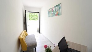 A room with a desk, chair, and a painting on the wall.
