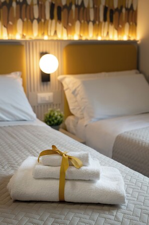 Una habitación de hotel con una cama bien hecha, una lámpara de noche y una lámpara de pared.