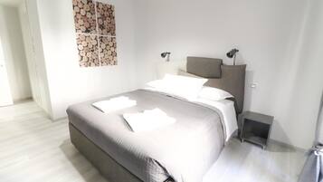 A bedroom with a bed, bedside tables, a headboard, and a wall-mounted artwork.