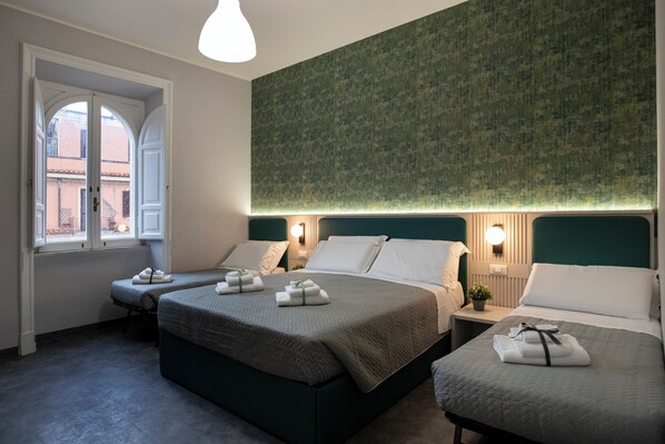 Ein Hotelzimmer mit zwei Betten, einem Fenster mit Blick und einer Wand mit Grüntönen.
