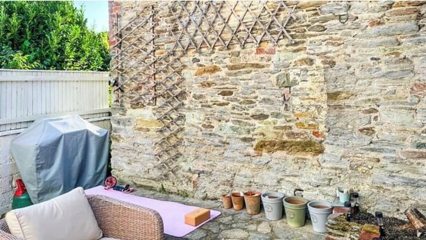 A stone wall with a lattice, outdoor furniture, and potted plants.