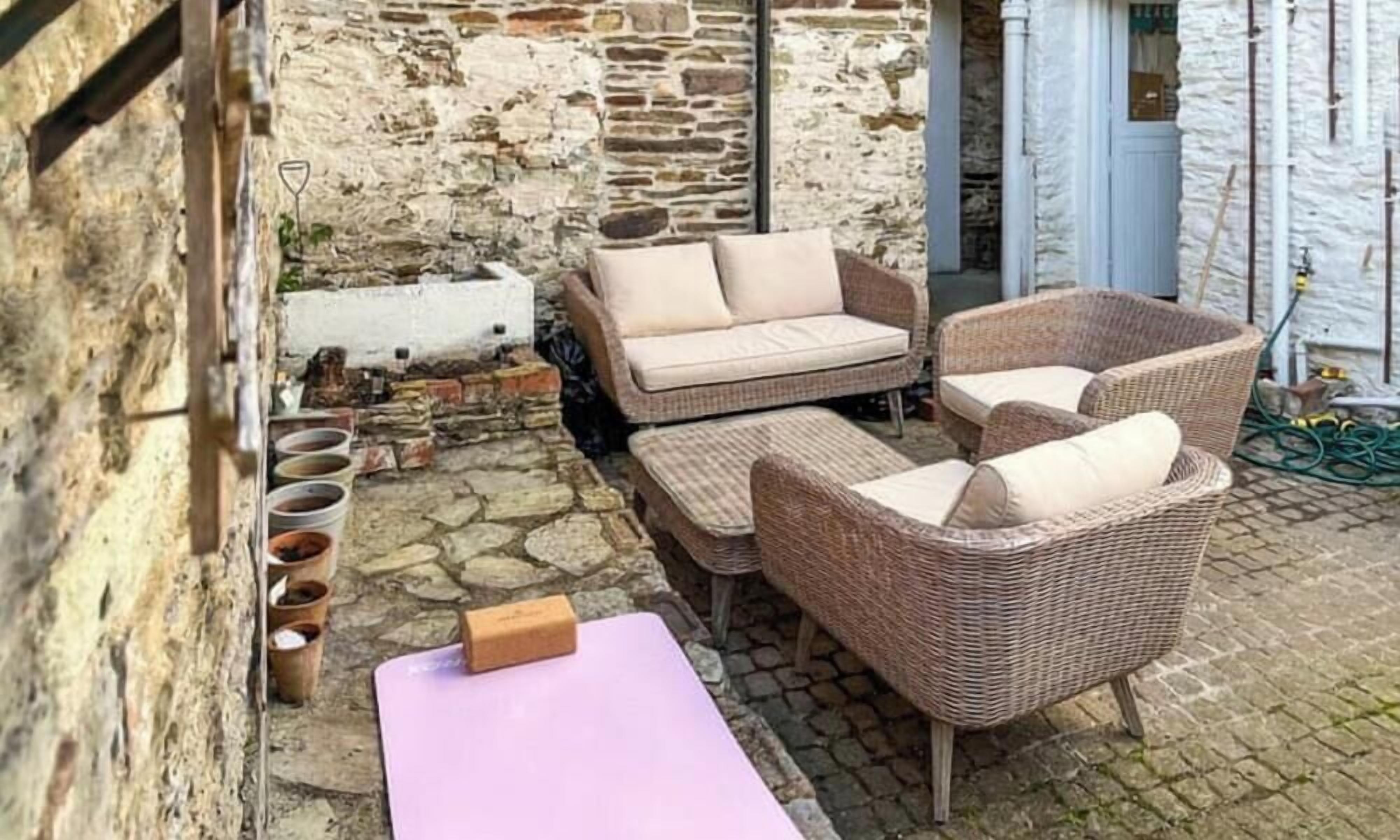 A rustic outdoor seating area with wicker furniture and a stone wall backdrop.