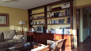 Un salon comprenant un canapé, une table basse, un téléviseur et une bibliothèque remplie de livres et de DVD.
