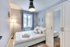 Une chambre à coucher avec un lit, une lampe de chevet, une armoire et une fenêtre avec des rideaux.