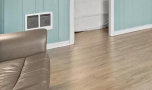 A room with a wooden floor, a brown leather sofa, and light blue walls.
