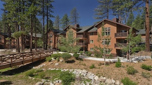 A multi-story lodge with balconies, surrounded by trees and a wooden bridge. - Mountain & Lake Vacation with Spacious 2BR at South Shore (Zephyr Cove)