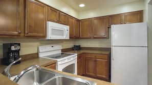 A kitchen with wooden cabinets, a white microwave, a stove, a refrigerator, and a coffee maker. - Mountain & Lake Vacation with Spacious 2BR at South Shore (Zephyr Cove)
