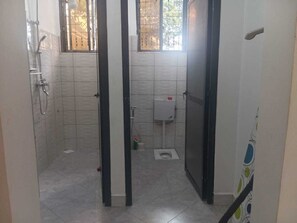 A small, tiled bathroom with a shower, toilet, and window. - Your Hidden Escape Near Kilimanjaro 🌿 (Boma Ng'ombe)