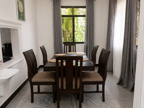 A dining room with a rectangular table, six chairs, and a window with curtains. - Your Hidden Escape Near Kilimanjaro 🌿 (Boma Ng'ombe)
