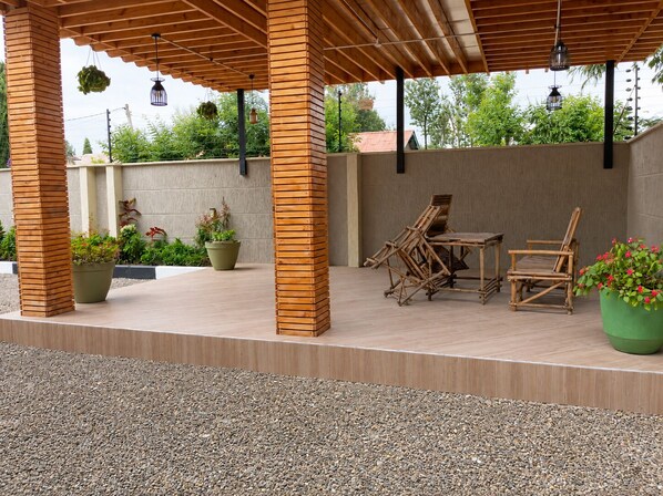 An outdoor patio area with wooden furniture, potted plants, and a pergola structure. - Your Hidden Escape Near Kilimanjaro 🌿 (Boma Ng'ombe)