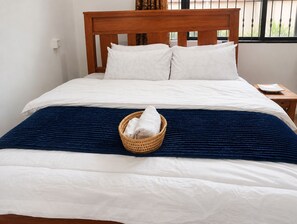A neatly made bed with white linens, a blue blanket, and a basket with a white towel. - Your Hidden Escape Near Kilimanjaro 🌿 (Boma Ng'ombe)
