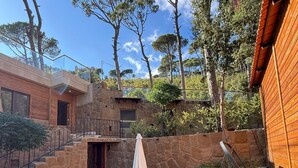 A patio with a wooden table and chairs, a swing, and a stone wall.