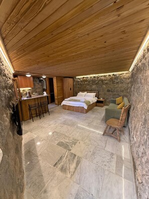 Un dormitori amb llit, sofà, zona de dinar i paret de pedra.
