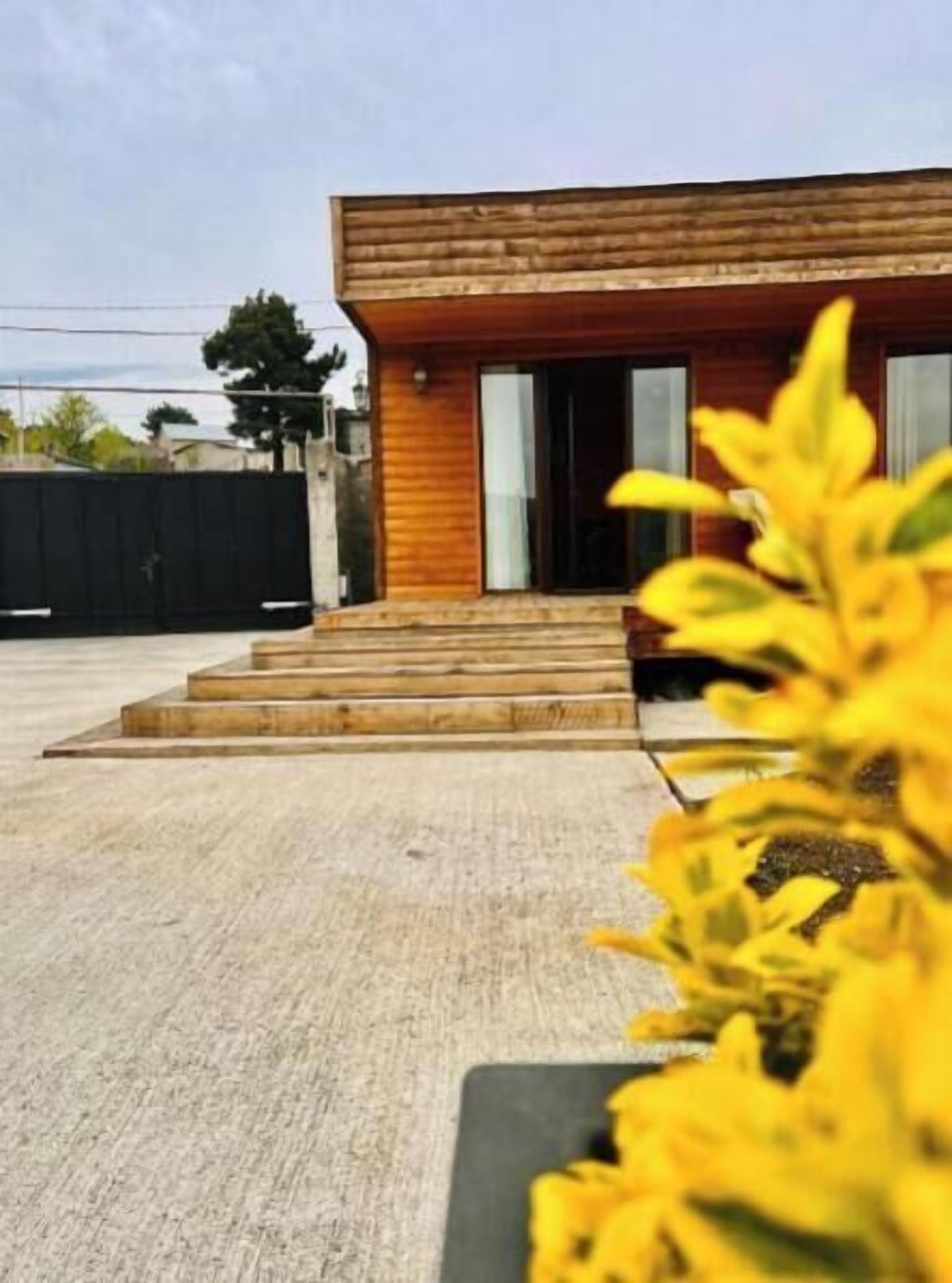 Un edificio moderno con fachada de madera, una serie de escalones que conducen a la entrada y un suelo de concreto.