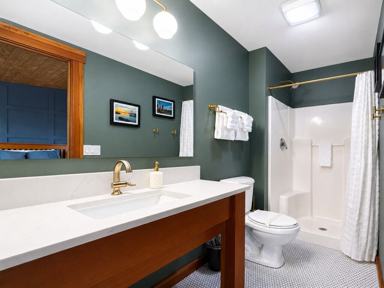 A bathroom with a white sink, gold faucet, and a shower curtain.
