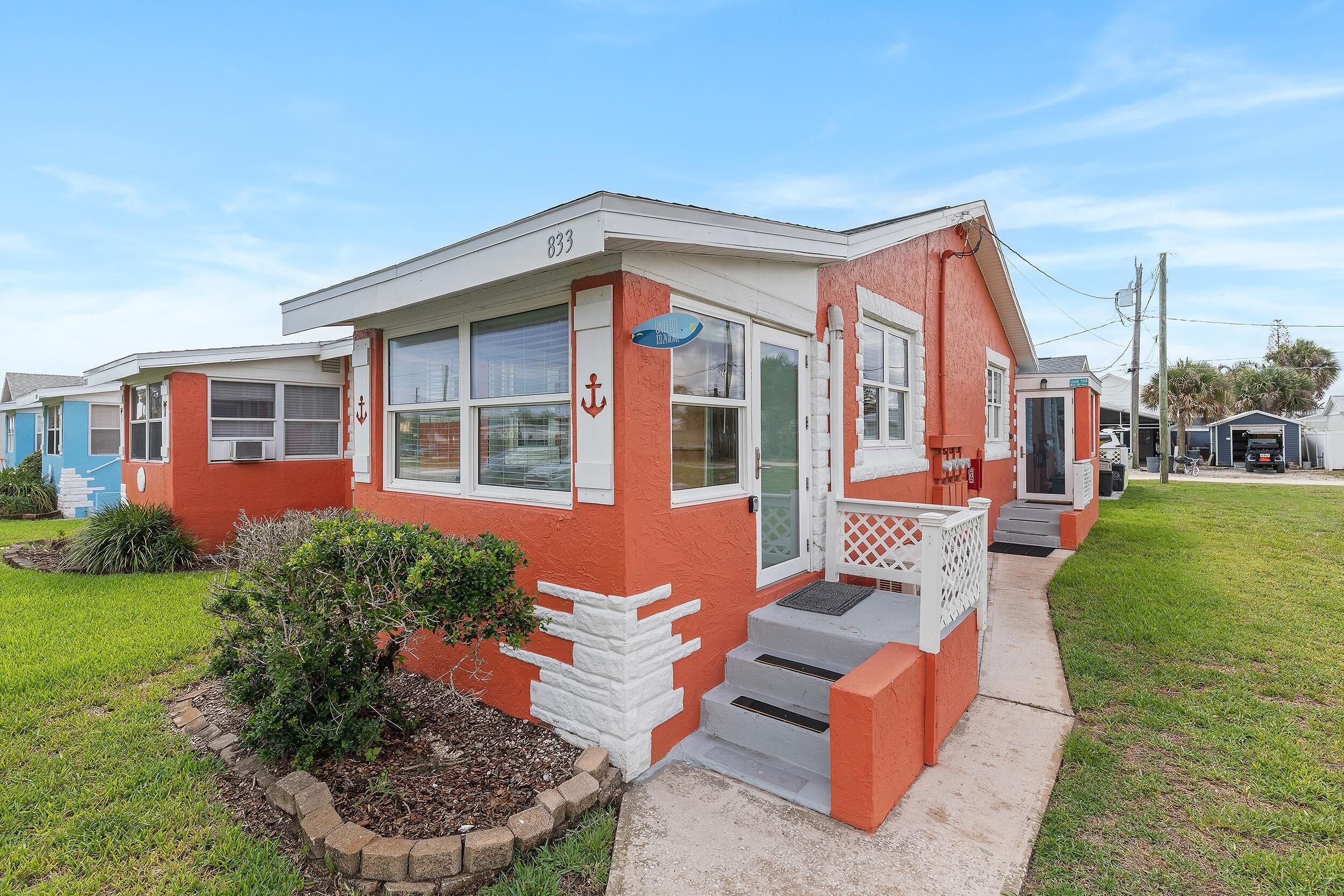 A single-story house with a red and white exterior, a front porch, and a small garden.