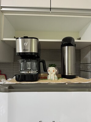 Cuina amb una cafetera, un termo i una tassa de ceràmica al taulell.