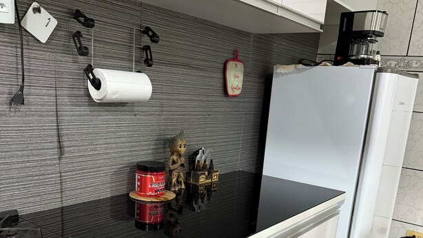 A kitchen with a gas stove, a refrigerator, and a wall-mounted coffee maker.