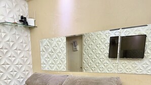 A sofa bed with a textured wall and a flat-screen TV mounted above it.