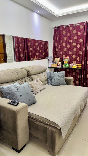 A bedroom with a large bed, a sofa, and a small table with various items.
