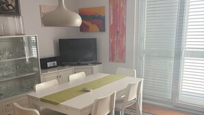 A modern dining area with a white table, chairs, and a central light fixture. - Elegant penthouse apartment with a view of the sea and two terraces in Rovinj (Rovinj)