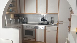A compact kitchen with white cabinetry, a built-in oven, a dishwasher, and a coffee maker. - Elegant penthouse apartment with a view of the sea and two terraces in Rovinj (Rovinj)