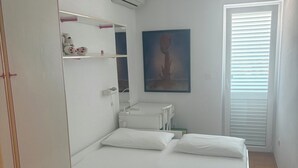 A bedroom with a bed, a wardrobe, a bedside table, a wall-mounted air conditioner, and a window with blinds. - Elegant penthouse apartment with a view of the sea and two terraces in Rovinj (Rovinj)