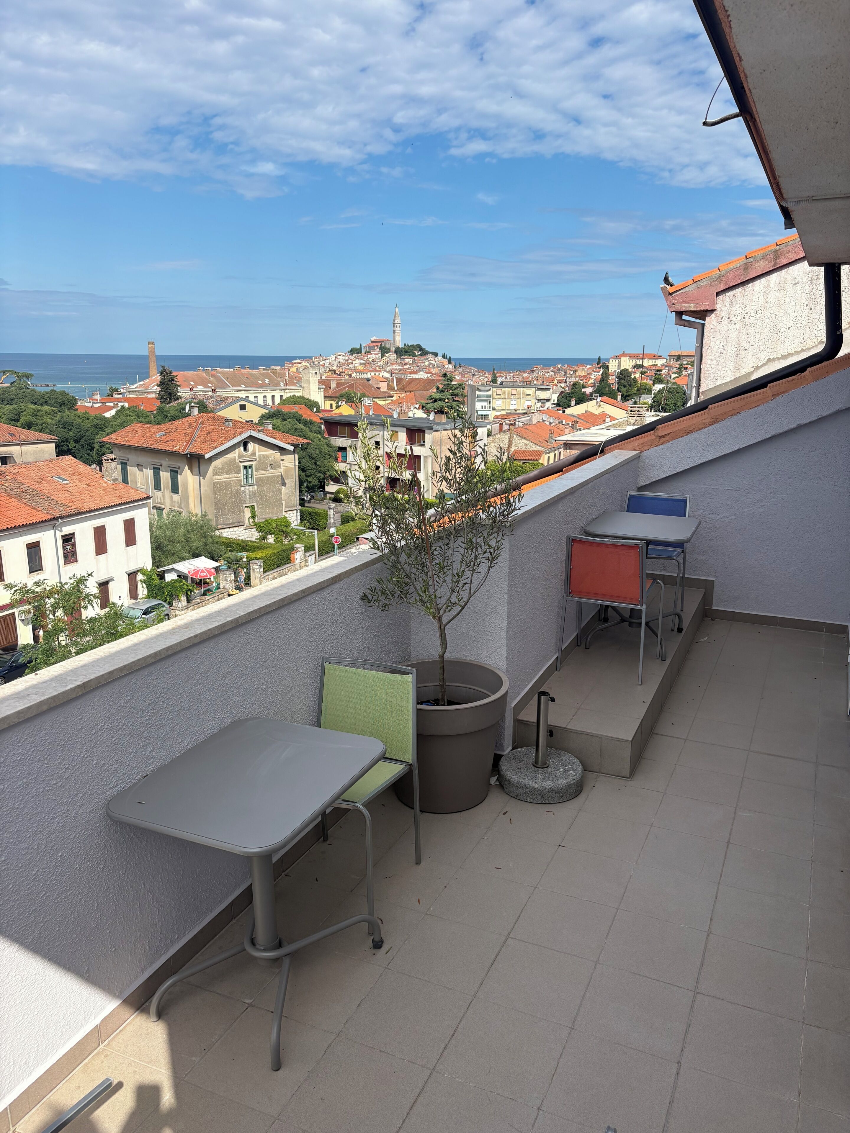 Un balcone con vista sulla città, un tavolo, sedie e una pianta in vaso.