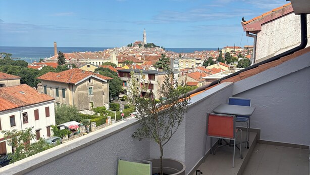 A balcony with a view of a cityscape, a table, chairs, and a potted plant. - Elegant penthouse apartment with a view of the sea and two terraces in Rovinj (Rovinj)