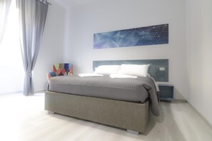 A modern bedroom with a large bed, a bedside table, a nightstand, and a wall art piece. - Superior Room for 1 to 4 people   Piazza Bologna (Roma)