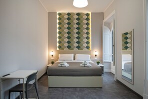 Ett hotellrum med en säng, sängbord, ett skrivbord och en stol.