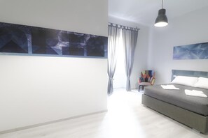 A modern bedroom with a bed, a chair, and artwork on the walls.