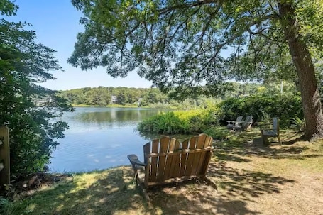 A lakeside setting with a wooden bench, chairs, and a picnic table.. Spacious 4BR house in perfect Chatham with AC