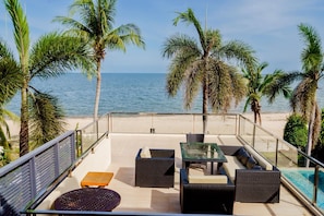 A terrace with outdoor furniture, a pool, and a view of the sea.