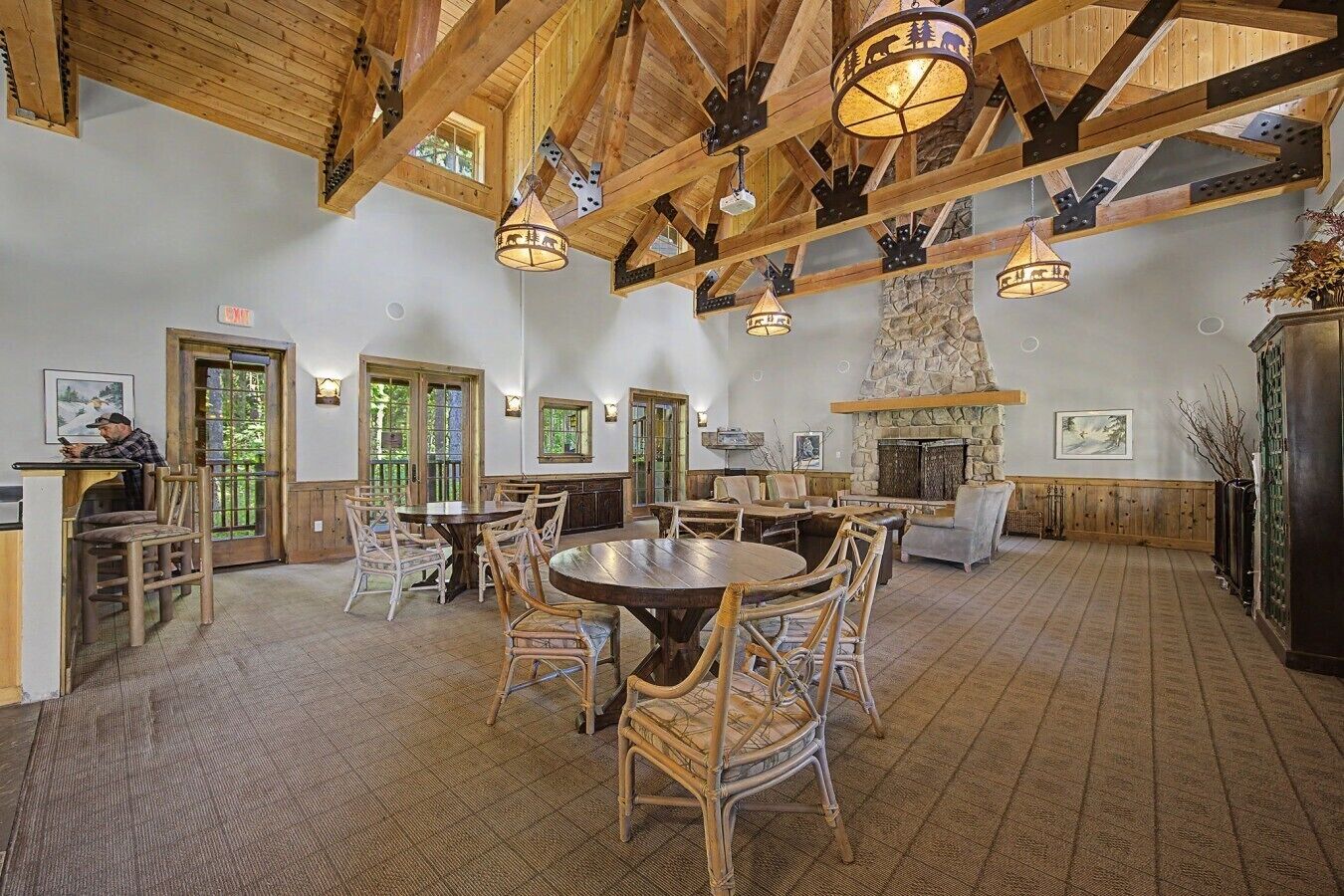 Une salle à manger spacieuse avec de hauts plafonds, des poutres en bois et une cheminée en pierre.
