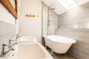 Un bagno con due lavandini, una vasca freestanding, una doccia e un lucernario.