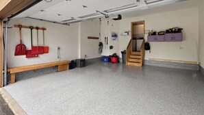 En garage med bænk, trætrap og lilla opbevaringsskabe.