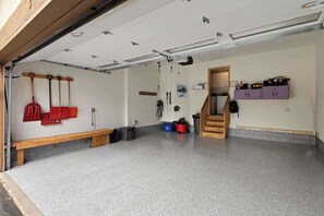 Eine Garage mit einer Sitzbank, einer Holztreppe und violetten Schränken.