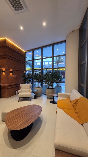 Una sala de estar moderna con un ventanal grande, un sofá, una mesa de centro y una pared de ladrillo decorativa.