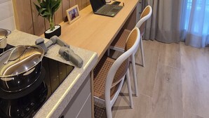 Una cocina moderna con estufa integrada, una encimera amplia y un rincón de comedor con dos sillas.