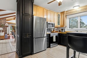 A modern kitchen with stainless steel appliances, wooden cabinets, and a large window.