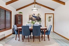 A dining room with a wooden table, blue chairs, a wooden cabinet, and a painting on the wall. - "Chalet" lake house/walking path/fenced yard/dock (Winter Haven)