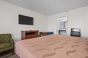 A hotel room with a bed, a television mounted on the wall, a desk, a chair, and a microwave. - Economy Inn & Suites (Rantoul)